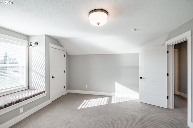 bonus room with carpet flooring, a textured ceiling, and vaulted ceiling