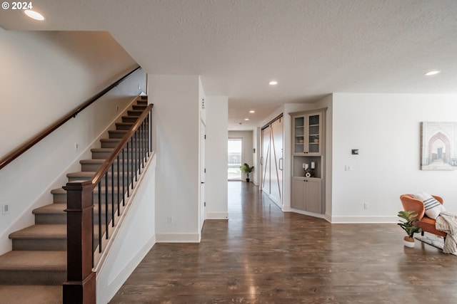 foyer entrance with a textured ceiling and dark hardwood / wood-style floors