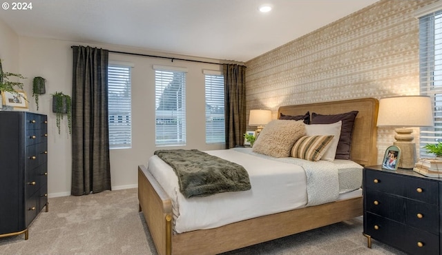 bedroom featuring wallpapered walls, baseboards, and light carpet