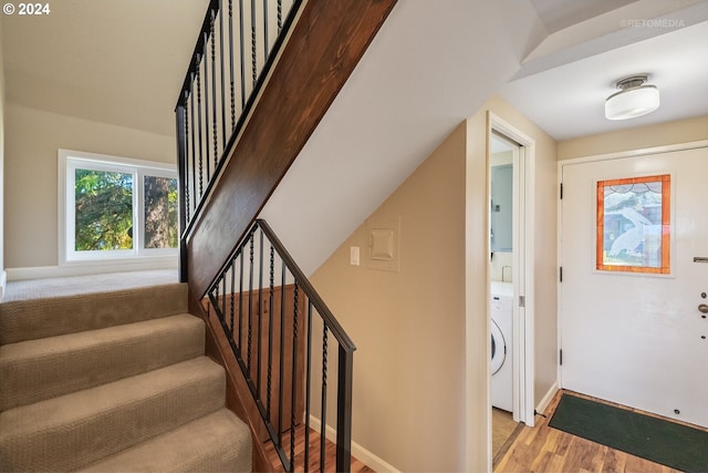 stairs with hardwood / wood-style floors and washer / dryer