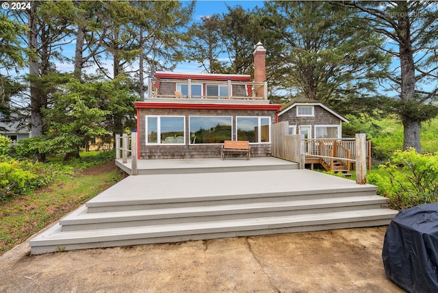 back of property featuring a balcony and a deck