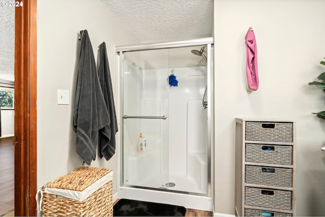 bathroom with a textured ceiling, an enclosed shower, and wood-type flooring