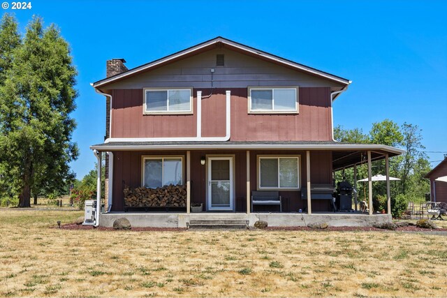 view of front of home with a porch, a chimney, and a front lawn