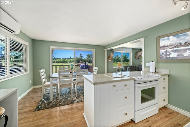 kitchen featuring white electric stove, a wall unit AC, white cabinets, light countertops, and light wood-type flooring