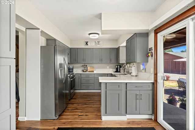 kitchen with gray cabinetry, dark hardwood / wood-style flooring, stainless steel appliances, sink, and kitchen peninsula