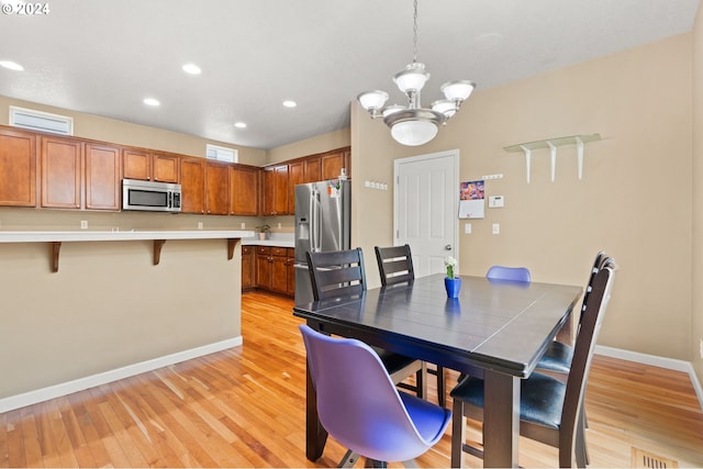 dining space featuring light hardwood / wood-style floors and a chandelier