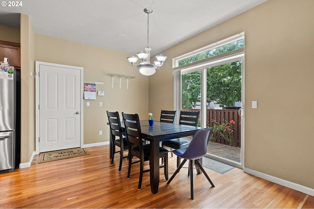 dining space with light hardwood / wood-style flooring and a chandelier