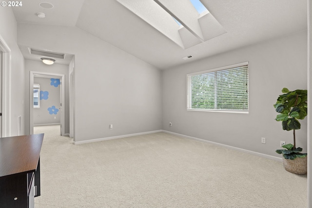 carpeted spare room with vaulted ceiling with skylight