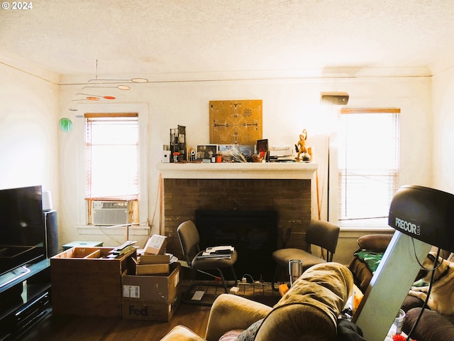 living room with a fireplace, cooling unit, ornamental molding, and a textured ceiling