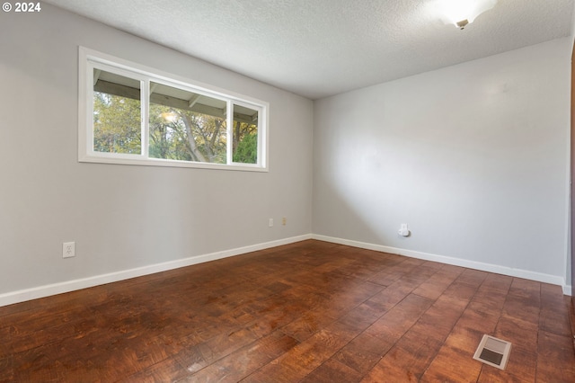 spare room with dark hardwood / wood-style flooring and a textured ceiling