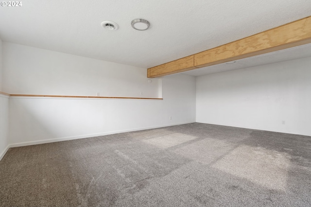 carpeted empty room featuring beam ceiling and a textured ceiling