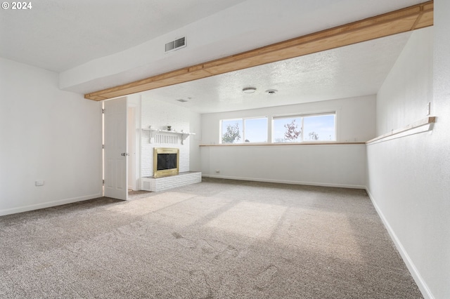 unfurnished living room with light colored carpet, a textured ceiling, and a fireplace