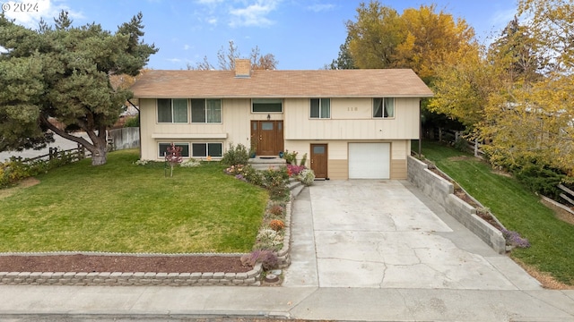 raised ranch featuring a garage and a front lawn