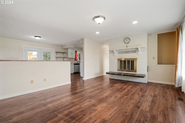 unfurnished living room with dark wood-type flooring, a fireplace, and a textured ceiling