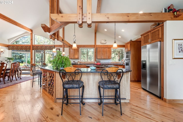 kitchen featuring appliances with stainless steel finishes, hanging light fixtures, and light hardwood / wood-style flooring