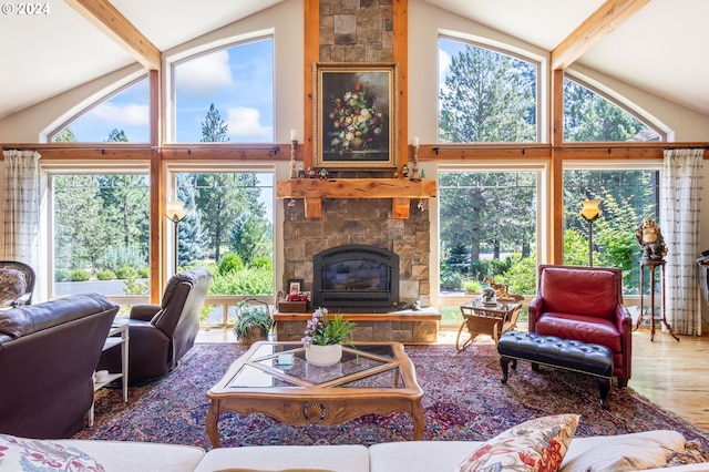 living room with a stone fireplace, beam ceiling, and a wealth of natural light