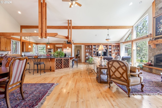 living room with beamed ceiling, high vaulted ceiling, ceiling fan, and light hardwood / wood-style flooring