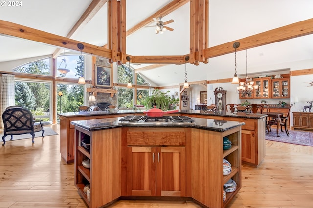 kitchen featuring decorative light fixtures, a stone fireplace, a center island, and stainless steel gas stovetop