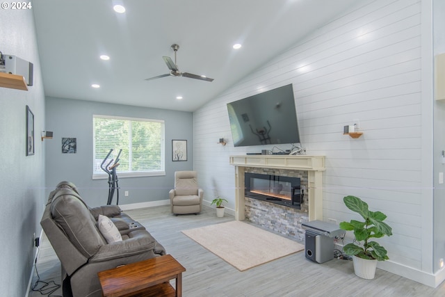 living room featuring light hardwood / wood-style flooring, vaulted ceiling, a fireplace, and ceiling fan