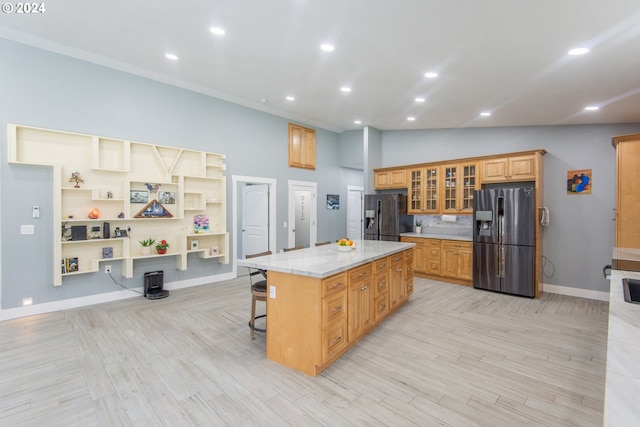 kitchen with a kitchen breakfast bar, light stone counters, a kitchen island, and stainless steel refrigerator with ice dispenser