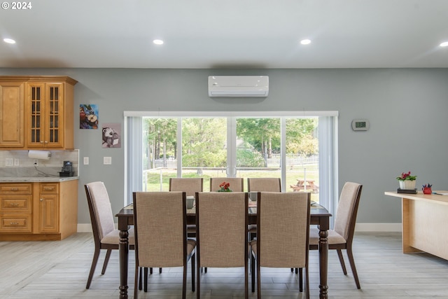 dining area with light hardwood / wood-style flooring, an AC wall unit, and a wealth of natural light