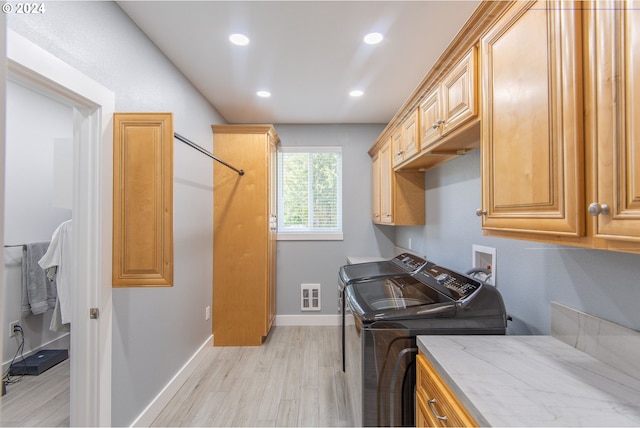 laundry room featuring cabinets, washer and dryer, and light hardwood / wood-style floors