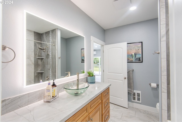 bathroom with vanity, tiled shower, and toilet