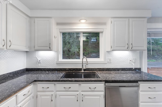 kitchen with stainless steel dishwasher, white cabinetry, sink, and dark stone counters