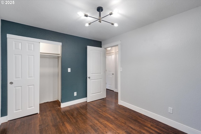 unfurnished bedroom with a chandelier, dark hardwood / wood-style flooring, and a closet