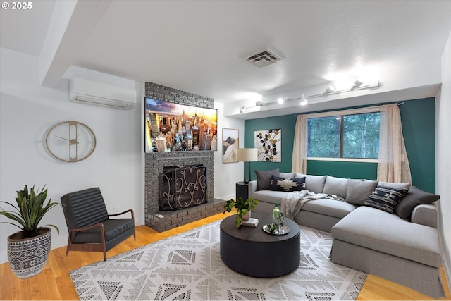 living room with hardwood / wood-style floors, a wall mounted air conditioner, and a brick fireplace