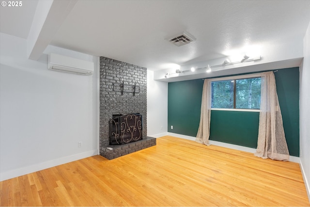 unfurnished living room featuring an AC wall unit, a fireplace, and hardwood / wood-style floors