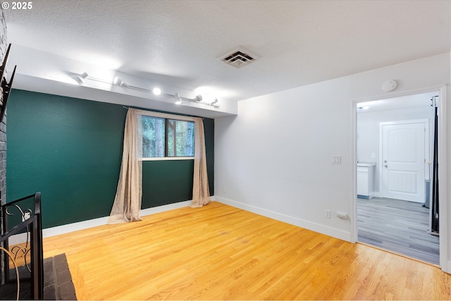 empty room with wood-type flooring and a textured ceiling