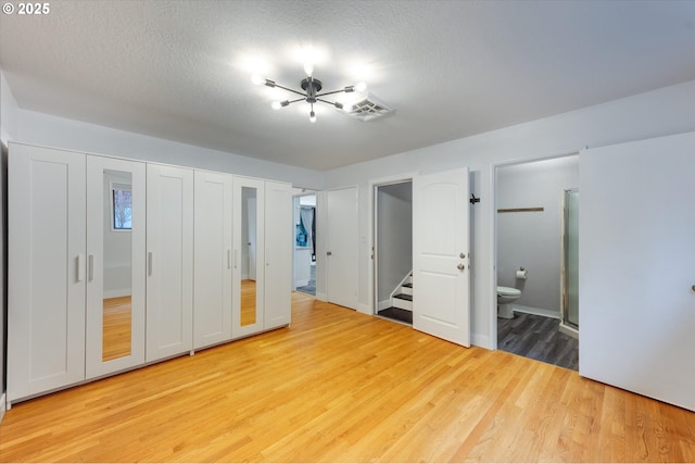 unfurnished bedroom with wood-type flooring, a textured ceiling, and connected bathroom