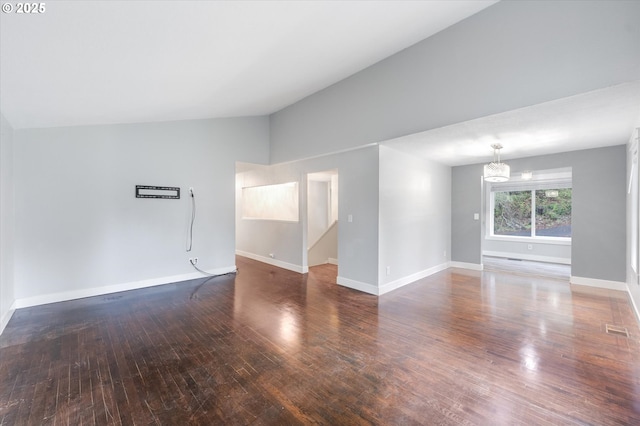 spare room featuring vaulted ceiling, dark wood-type flooring, and a notable chandelier