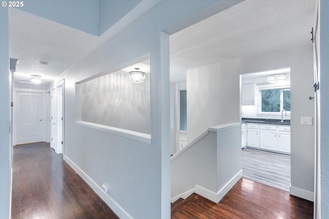 hallway featuring a textured ceiling, dark hardwood / wood-style floors, and sink