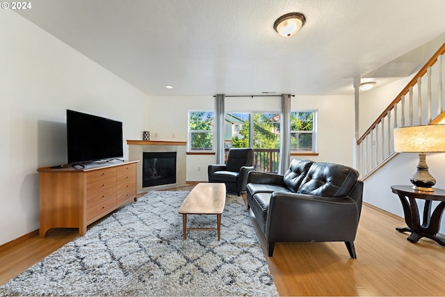 living room with a tile fireplace, light hardwood / wood-style floors, and a textured ceiling