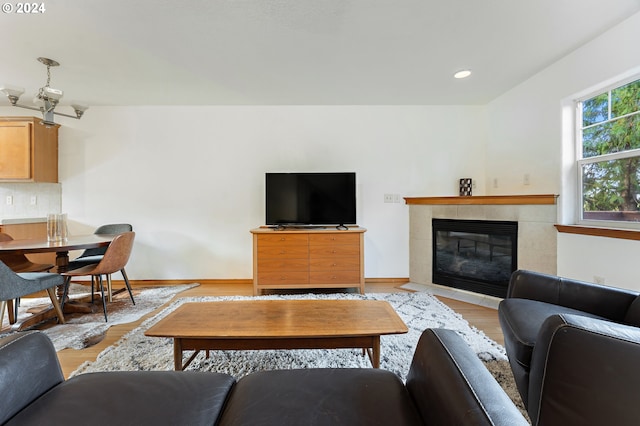 living room featuring a tile fireplace, light hardwood / wood-style floors, and a chandelier