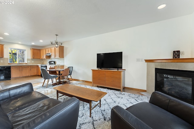 living room with a tiled fireplace, sink, and light tile patterned flooring