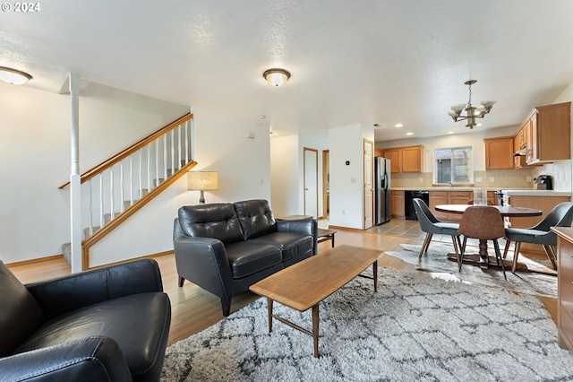 living room featuring a textured ceiling, light hardwood / wood-style floors, and a notable chandelier