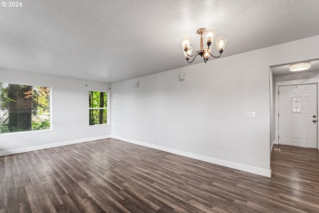 spare room with a textured ceiling, a notable chandelier, and hardwood / wood-style floors