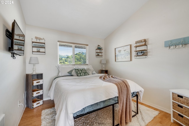 bedroom featuring light wood-type flooring and vaulted ceiling