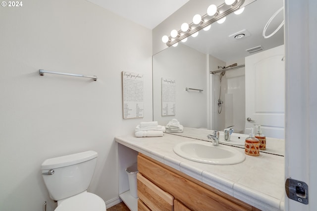 bathroom featuring toilet, vanity, and walk in shower