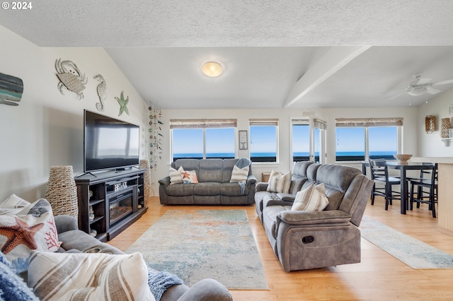 living room with a textured ceiling, light hardwood / wood-style flooring, a wealth of natural light, and ceiling fan