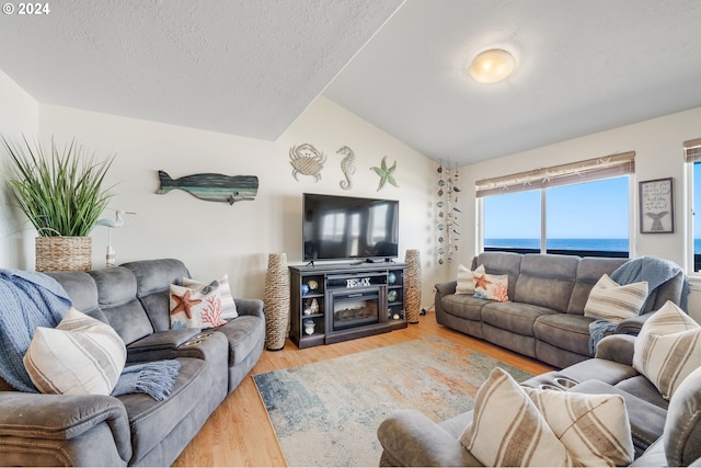 living room featuring a textured ceiling, light hardwood / wood-style flooring, and lofted ceiling