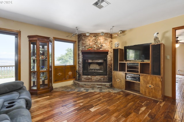 living room with ceiling fan, wood-type flooring, a fireplace, and a wealth of natural light