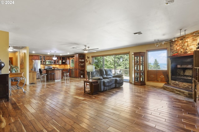 living room featuring a fireplace, wood-type flooring, and ceiling fan