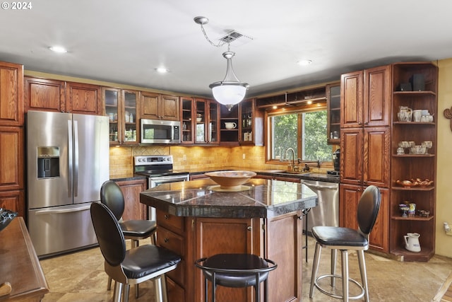 kitchen featuring a breakfast bar, a center island, sink, appliances with stainless steel finishes, and decorative light fixtures