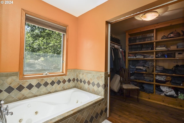 bathroom with wood-type flooring and tiled tub