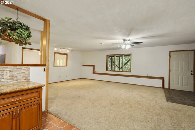 unfurnished living room with a textured ceiling, light colored carpet, ceiling fan, and rail lighting