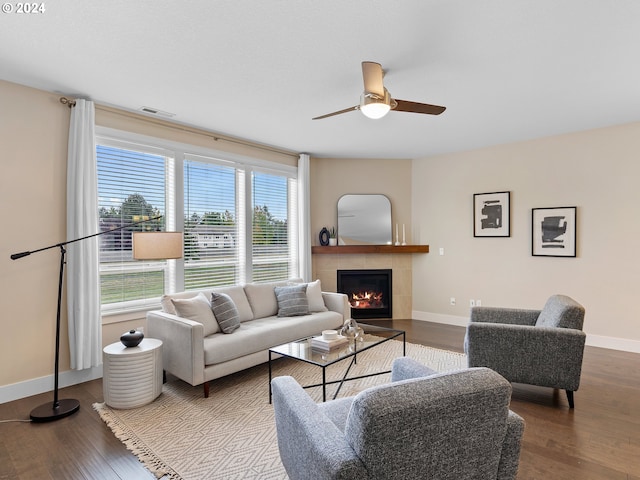 living room with hardwood / wood-style floors, a tile fireplace, and ceiling fan